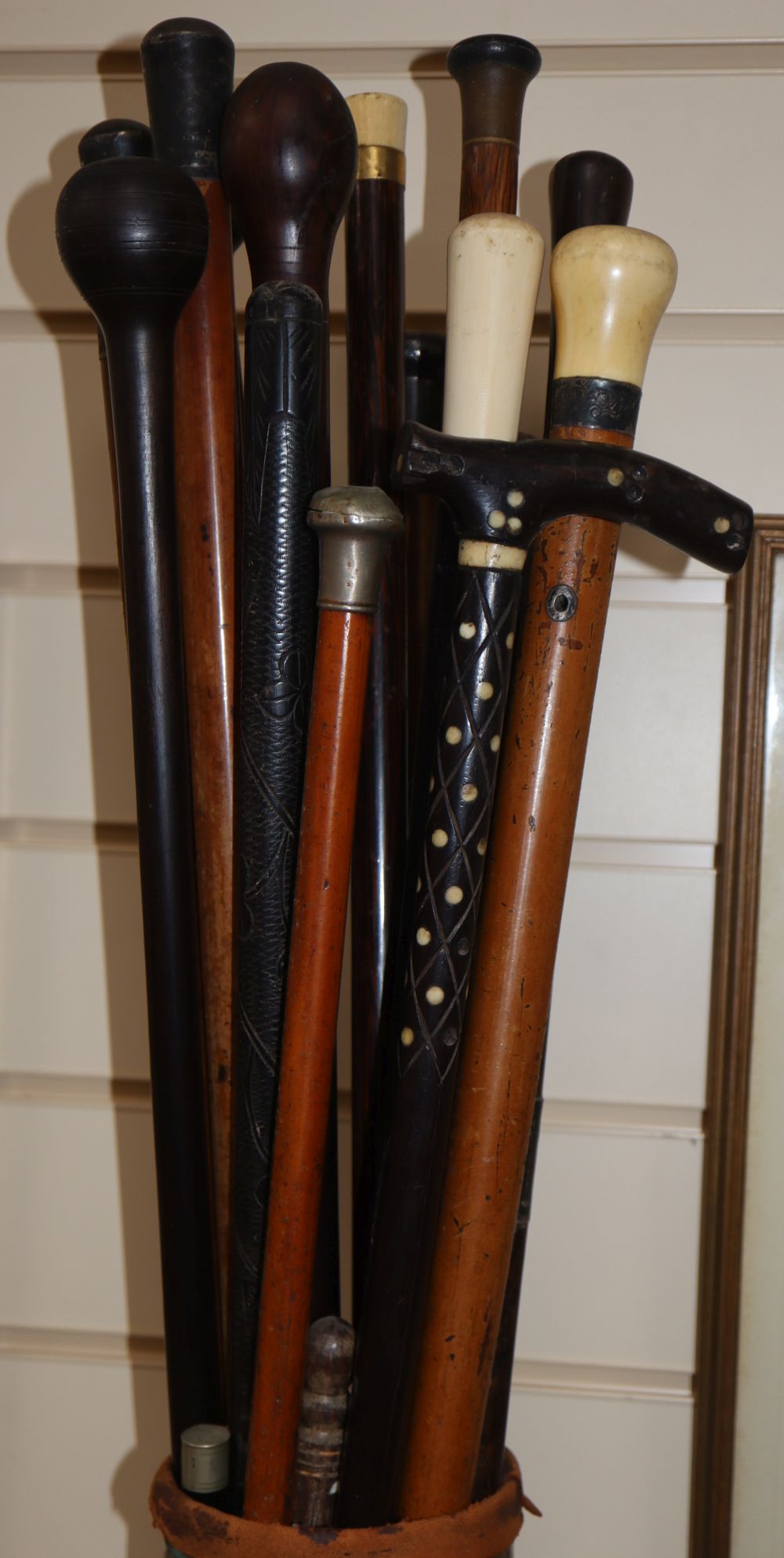 A group of walking canes, some with silver or ivory handles, in an artillery shell case stand